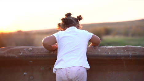 young south african girl looking over a bridge barrier waving at her reflection at golden hour