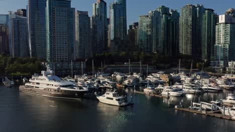 drone aerial shot over the vancouver marina and cityscape moving towards several skyscrapers - canada