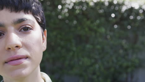 half face of happy caucasian woman standing and smiling in sunny garden, copy space, slow motion