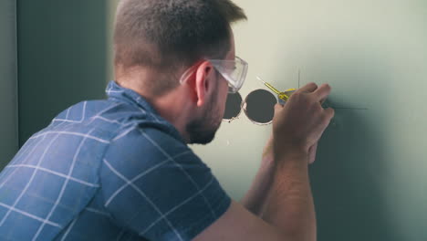 electrician repairs plug on with screwdriver in light room