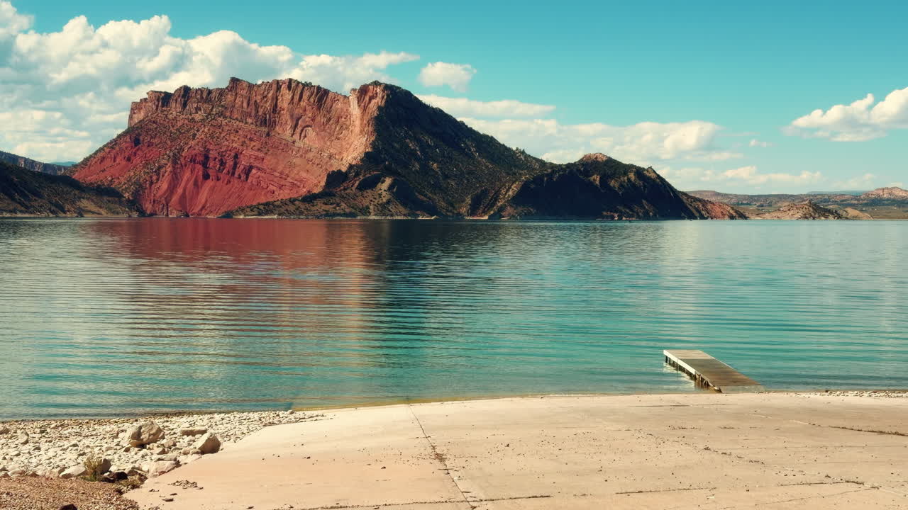 Rocky Mountain Reflected Over Calm Lake With A Boat Ramp. Slow Motion Shot