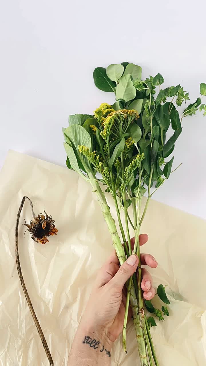 Hand holding a bouquet of wildflowers and dried flower