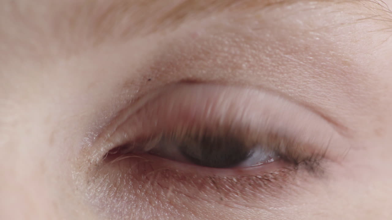 가까이에서 아름다운 파란 눈을 가진 여성이 카메라를 바라보며 눈을  ⁇ 박이는 아름다움