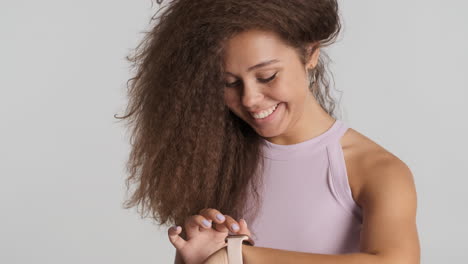 una mujer caucásica de cabello rizado revisando las notificaciones en su reloj inteligente.