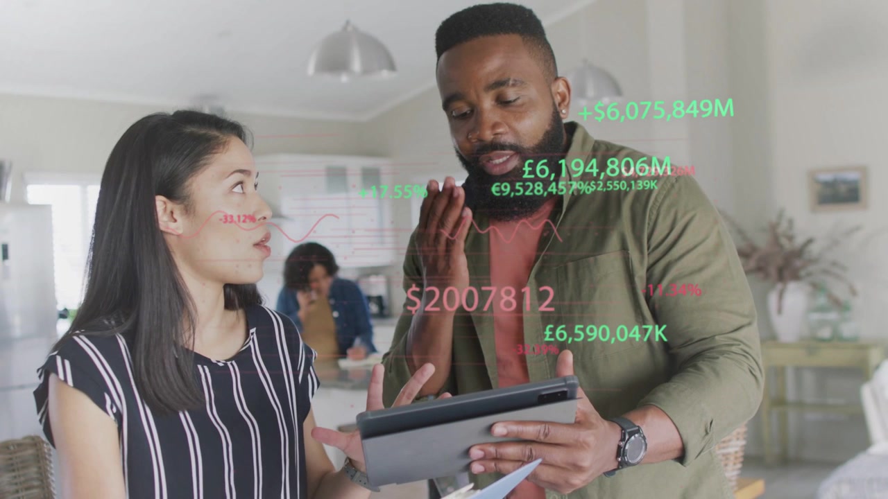 Kvinde peger på et ark, mand trykker på tablet, finansdiagrammer skifter, team afstemmer tal.