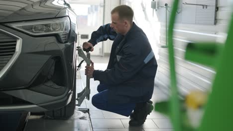 mechanic performing a wheel alignment process in a modern workshop. professional equipment is used to ensure accurate vehicle alignment for optimal performance and safety