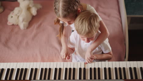 blonde little girl presses piano keys with crying brother