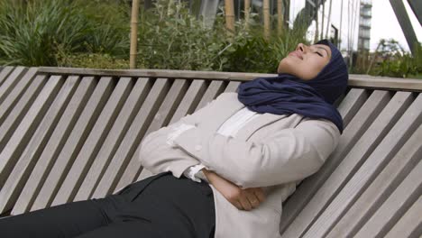 muslim businesswoman resting on bench outdoors in city gardens or park 1