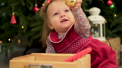 baby girl plays with christmas ornament
