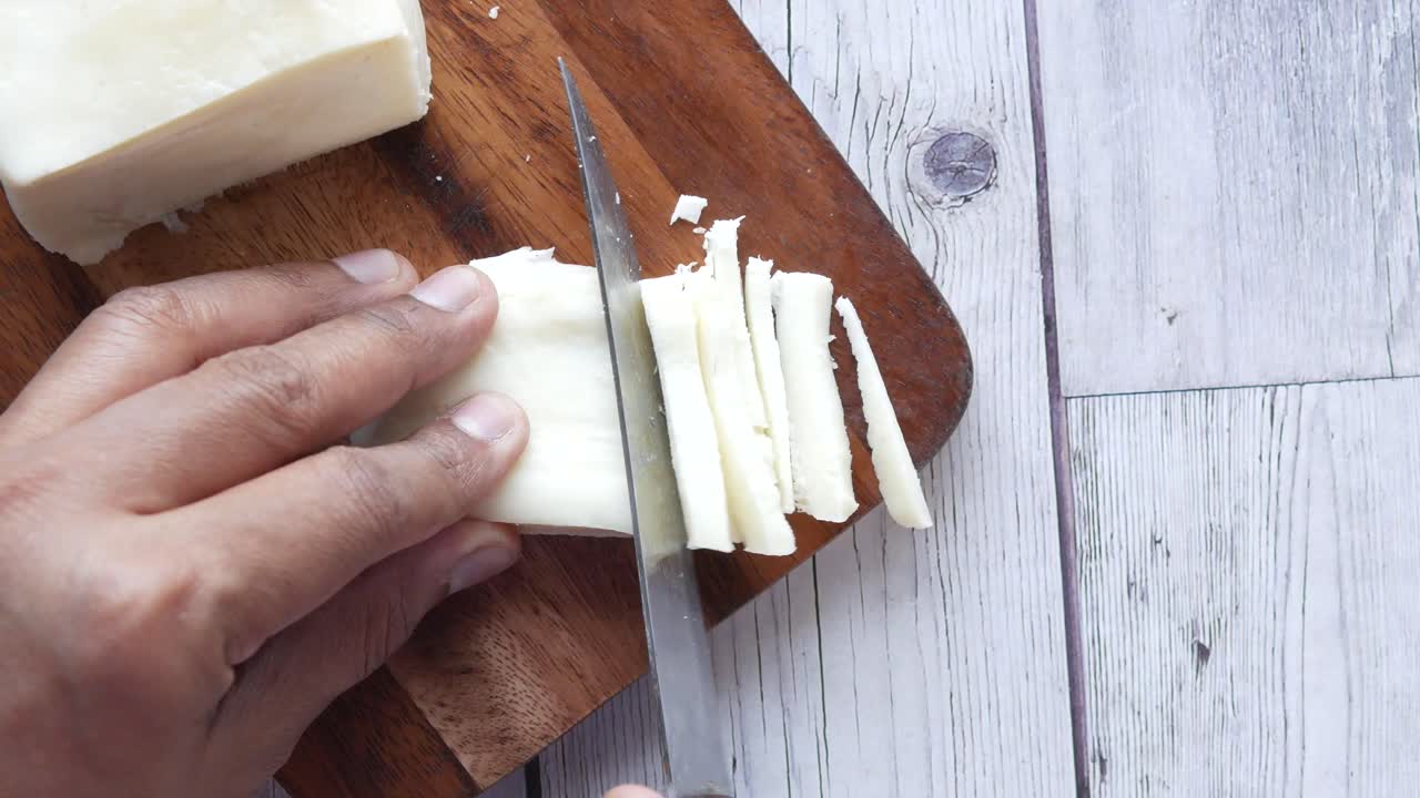cortar queso en rodajas en una tabla de madera