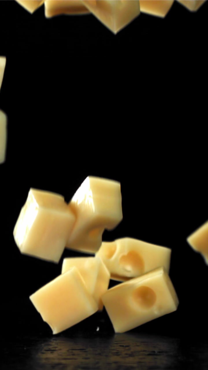 Cubes de fromage tombant au ralenti sur un fond noir