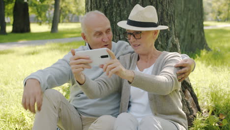 senior couple taking selfie in park