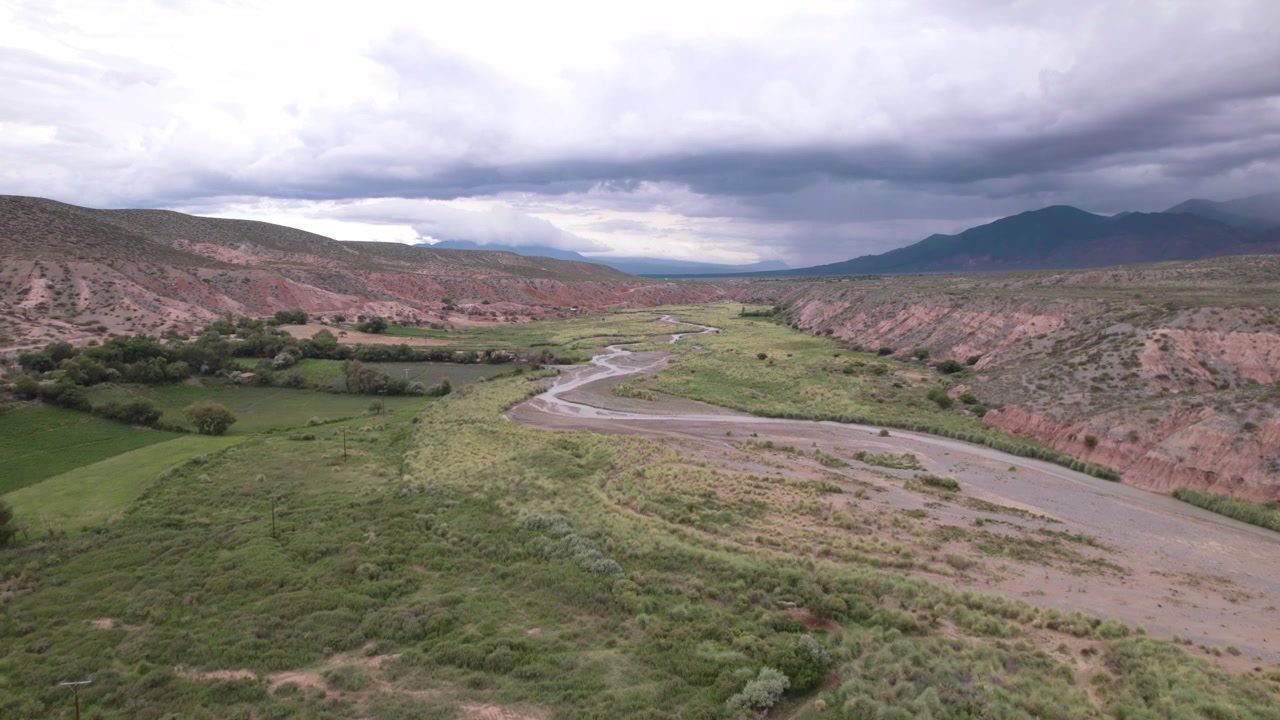 Vista aerea con drone 4K di La Poma, Salta, Argentina. Splendido paesaggio andino con montagne di roccia rossa, valli verdi e un fiume che attraversa lo spettacolare scenario del canyon