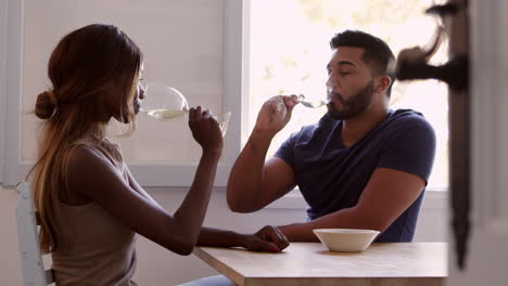 una joven pareja adulta se sienta bebiendo vino y hablando en la cocina, filmada en r3d