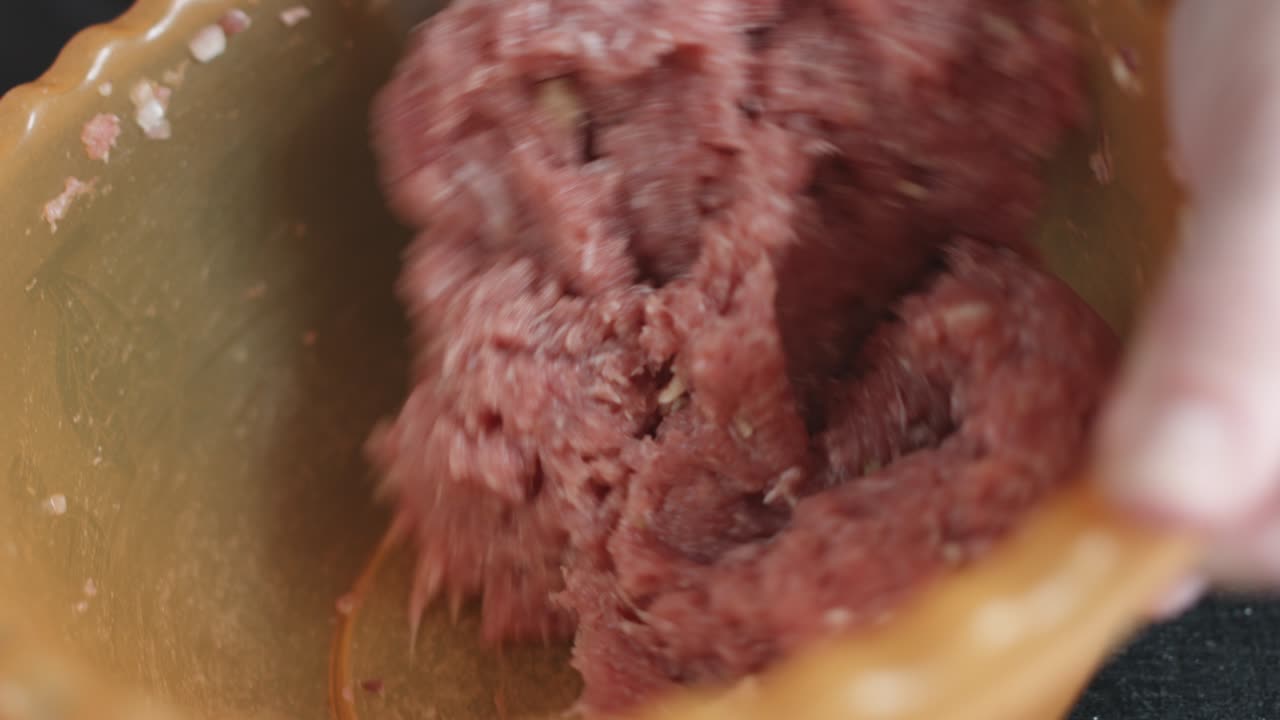 dos manos haciendo albóndigas de carne.