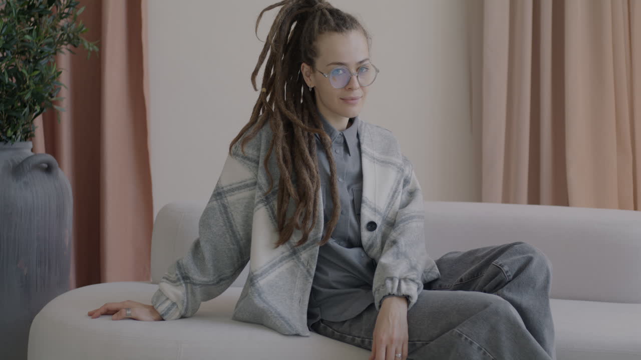 Woman Sitting on a Couch with Dreadlocks and Glasses