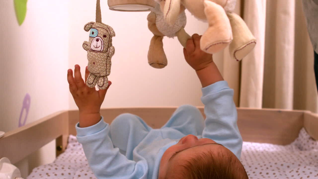 Bambino che gioca con il cellulare nella sua culla