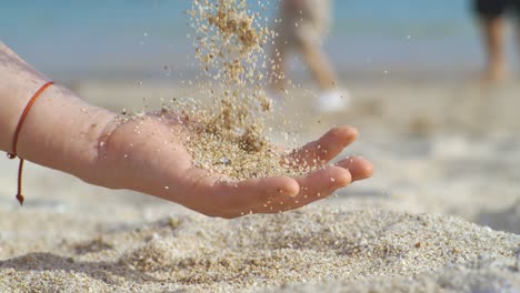 arena cayendo de la mano en cámara lenta en una playa. vacaciones y concepto de viaje. disparado en cámara súper cámara lenta 1000 fps.