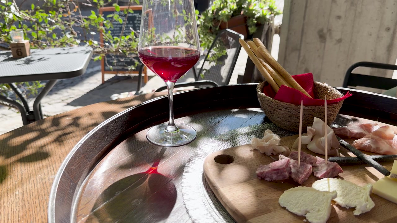Primo piano di vino rosso e antipasti italiani su un tavolo di legno sotto la luce solare intensa