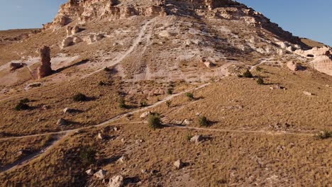 Aerial-dolly-approaching-rugged-and-arid-mountain-during-sunset-in-Cappadocia,-Turkey