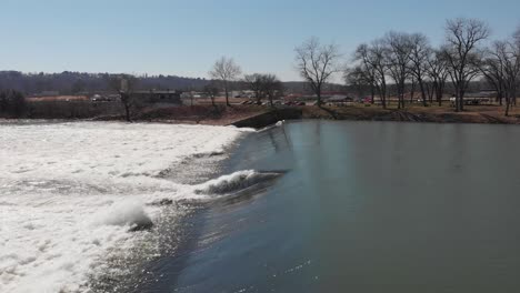 aerial view around a rushing river, hydroelectric power, sunny spring day, in arkansas, usa - low, circling, drone shot