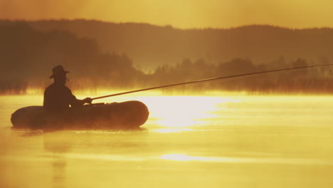 fisherman in the boat fishing with a rod in hands in the middle of the lake