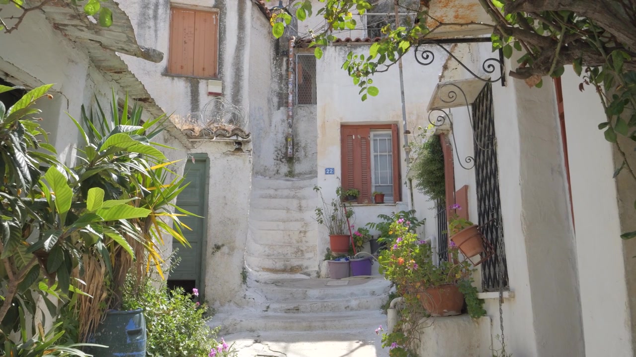 Via incantevole ad Anafiotika, Atene, Grecia, caratterizzata da architettura tradizionale bianca, piante in vaso e scale tortuose.