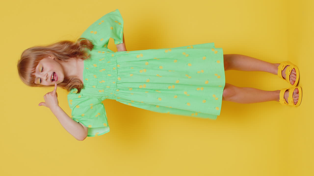 Bambina che fa il gesto del telefono, come per dire "ehi, richiamami", in una proposta pubblicitaria, verticale.