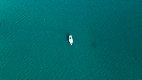 Aerial-orbit-around-anchored-yacht-in-green-blue-ocean-waters-with-slight-tide