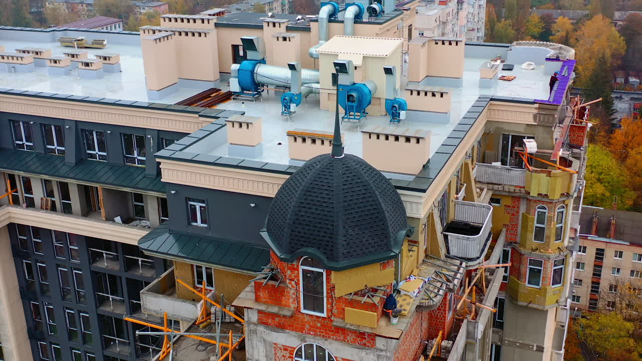 Construction of modern tower house. Workers build the on the top of multi-storey building. New high-rise architecture under construction in the city.