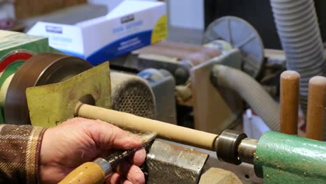 making wooden dowel rod on turning wooden lathe with chisel