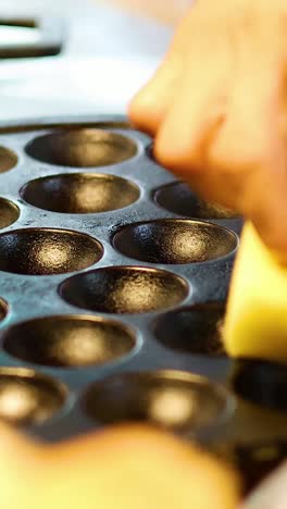 hands pouring batter into round cooking molds