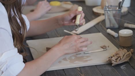 close-up of a master potter, clay cutting special tool. female artist cutting with a wooden loop tool