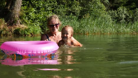 grandmother with small charming granddaughter bathe in lake