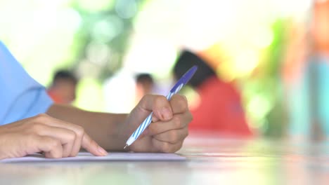 hand holding pen writing paper on table on bright daytime of sunlight