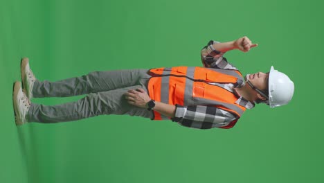 full body side view of angry asian male engineer with safety helmet shouting at someone while standing in the green screen background studio
