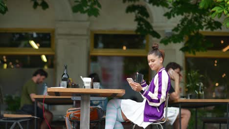 joven usando un teléfono inteligente en un café al aire libre