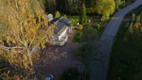 aerial view approaching a sunlit house with solar panel, autumn evening