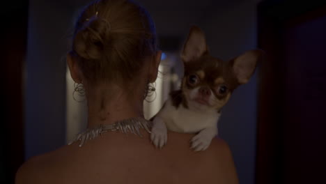 mujer llevando un chihuahua en el hombro en el pasillo de un hotel