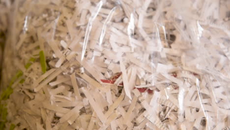 Close up pan over a bag of shredded paper waiting to be recycled
