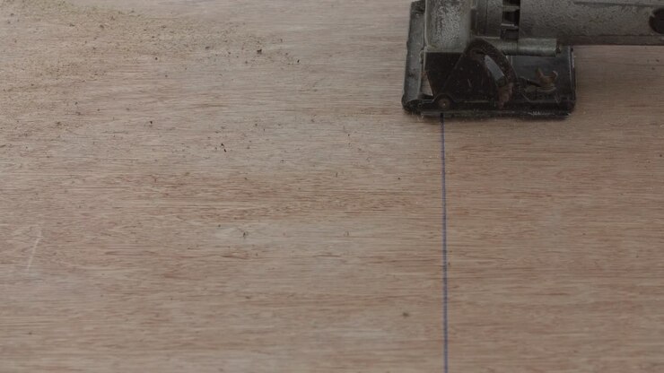 Construction worker cutting wood planks with circular electric saw outdoors