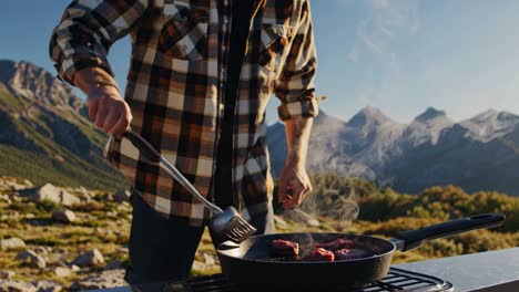 man cooking steak in the mountains