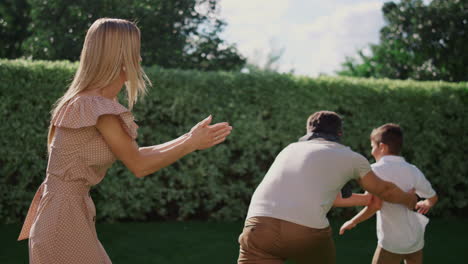 kids with parents playing blind man buff on backyard. family running in park