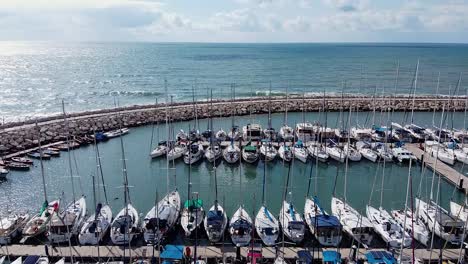 aerial view of tel aviv port with anchored sailboats on a sunny day, stunning coastal scenery, flyover