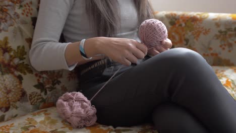 woman wraps yarn from disorganized spool into medium sized yarn ball