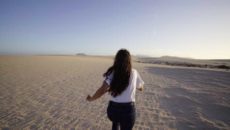 Young-multiracial-latin-woman-walk-in-barefoot-sandals-on-sand-dunes-Desert-hot-sunny-day,-slow-motion-happy-traveller-celebrating-life