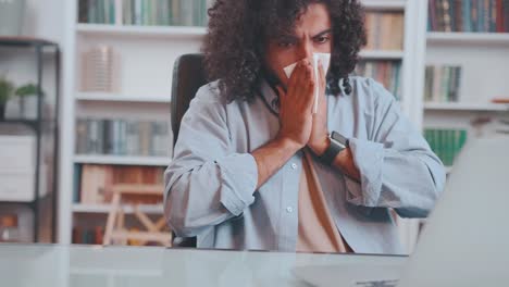 young unhealthy arabian man sneezes covering mouth with paper tissue