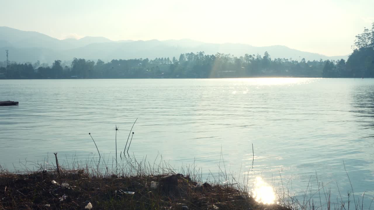 Beautiful view of a lake reflecting the sun with a faint haze over the mountains