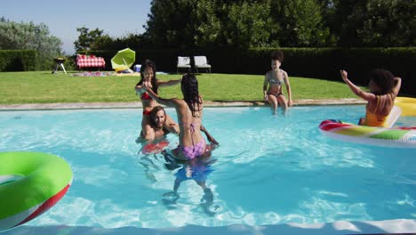 grupo diverso de amigos divirtiéndose jugando en la piscina