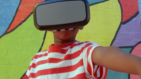 Vorderansicht-Eines-Afroamerikanischen-Schuljungen,-Der-Ein-Virtual-Reality-Headset-Gegen-Die-Wand-In-Der-Schule-Nutzt,-4k